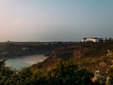 A coastal landscape with cliffs and a sandy beach with buildings on a hill at Villa 6 in Mullion