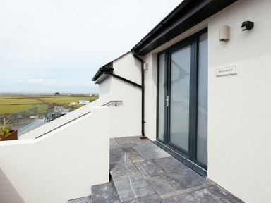 Stone steps leading to a glass door with a railing and a view of fields at Shearwater in Mullion