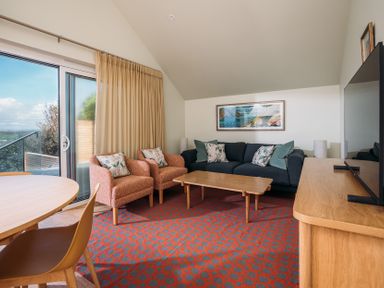 A living room with armchairs a sofa coffee table and a television at Shearwater in Mullion