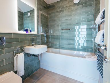 A bathroom with a sink towel rack and bathtub with shower at Shearwater in Mullion