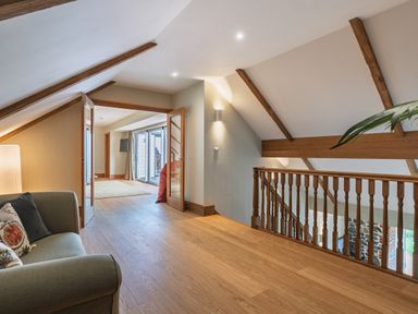 A hallway with a sofa and doors leading to the balcony at Trevean, Mullion