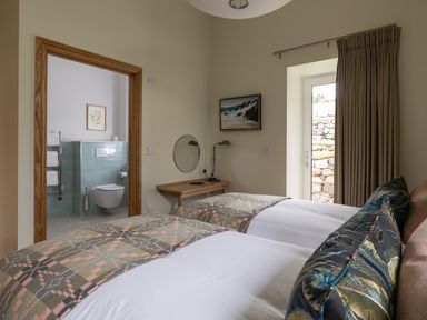 A bedroom with two beds and an en-suite bathroom at Trevean in Mullion
