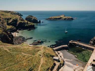 A coastline with a pier and sailboat at Trevean in Mullion