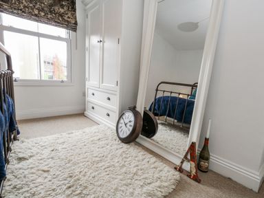 A bedroom with a mirror and a clock at Fisherman’s Cottage