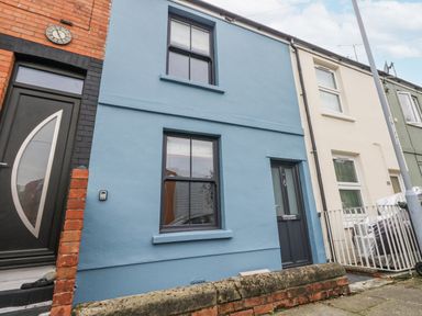 A blue house exterior with front door and windows at Fisherman’s Cottage