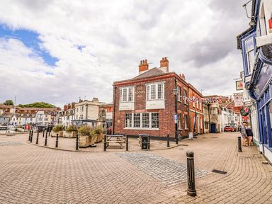 A pub building on a street with flags and lampposts at Fisherman’s Cottage in 