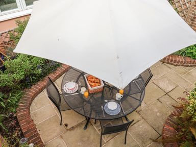 A patio table with four chairs under a white umbrella with breakfast items at Sea Crest in Aldeburgh