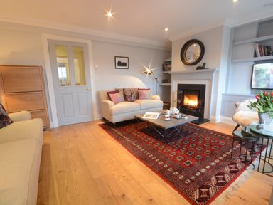 A living room with sofas a coffee table a fireplace and bookshelves at Sea Crest in Aldeburgh