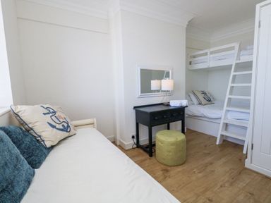 A bedroom with bunk beds a small desk with a lamp and a round stool at Flat 7 Sand Acres in Canford Cliffs
