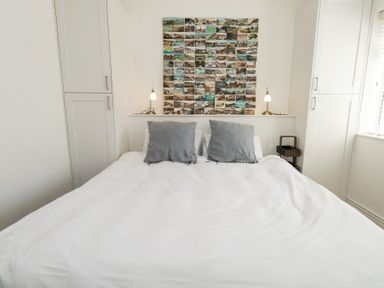 A bedroom with a double bed two gray pillows overhead collage and two bedside lamps at Flat 7 Sand Acres in Canford Cliffs