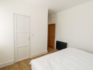 A bedroom with a bed a white door a wooden door and a black heater on the wall at Flat 7 Sand Acres in Canford Cliffs