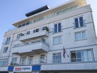 A multi-story residential building with balconies and a Tesco express store at the ground level at Flat 7 Sand Acres in Canford Cliffs