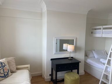 A room with a black desk and lamp with a mirror above and a bunk bed next to a white sofa at Flat 7 Sand Acres Canford Cliffs