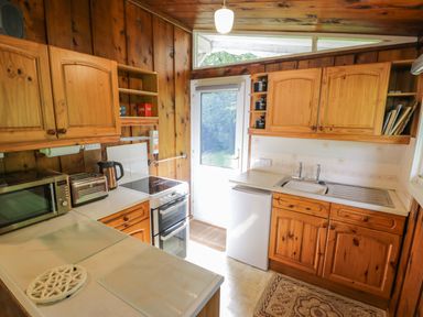 A kitchen with wooden cabinets and appliances at Ty Bedwen in Dinas Mawddwy