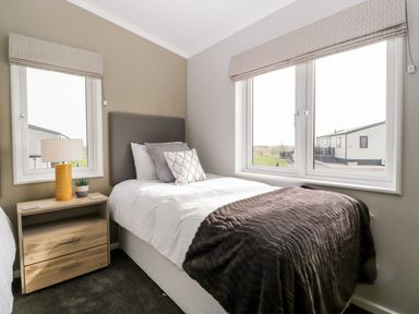 A bedroom with a single bed a bedside table with a lamp and a window at Summerdown Brean