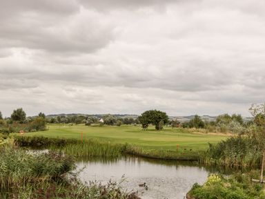 A golf course with a pond and ducks under a cloudy sky at Summerdown in Brean