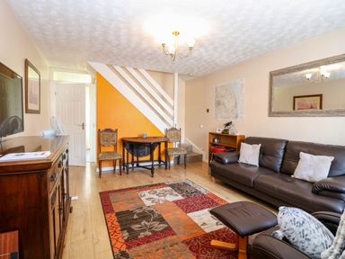 A living room with a sofa pillows a colorful rug wooden furniture and an orange accent wall at Sweetacres in Hemsby