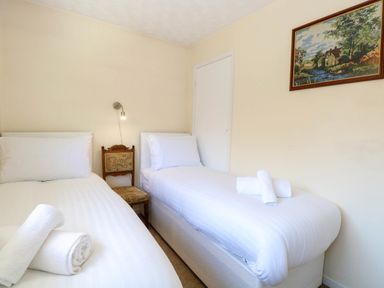 A bedroom with two single beds and rolled towels on each bed at Sweetacres in Hemsby