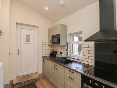 A kitchen with cabinets microwave sink stovetop and a door at Top Holme Cottage in Newbald