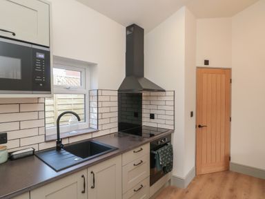 A kitchen with sink stove microwave and wooden door at Top Holme Cottage in Newbald