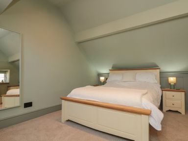 A bedroom with a double bed two bedside tables with lamps and a large mirror on the wall at Top Holme Cottage in Newbald