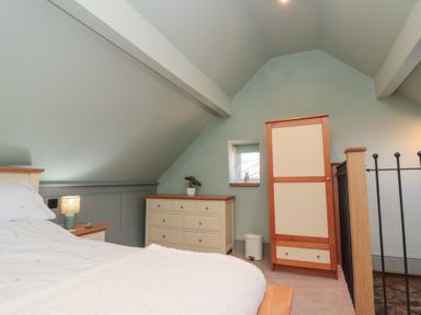 A bedroom with a bed bedside table lamp dresser wardrobe small window and sloped ceiling at Top Holme Cottage in Newbald