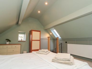 A bedroom with a bed and folded towels a chest of drawers a wardrobe and a staircase at Top Holme Cottage in Newbald