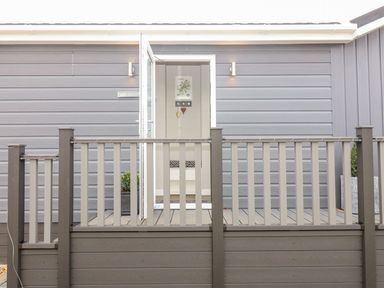 A gray wooden exterior with an open glass door and a porch with railing at The Gallops in Chipping Norton