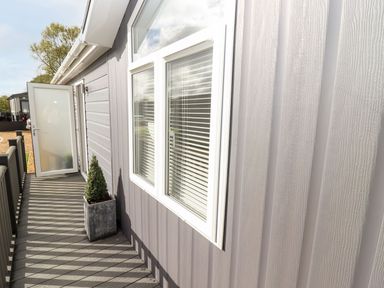An exterior walkway with a potted plant beside a window and an open door at The Gallops in Chipping Norton