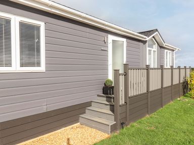 Exterior of a grey and brown house with steps leading to a white door and a railing fenced porch at The Gallops in Chipping Norton