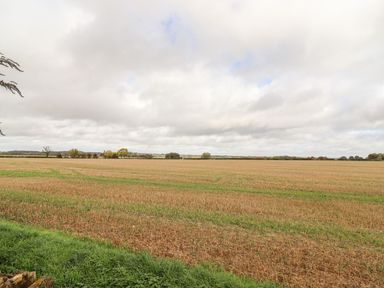 An open field with low vegetation and grass under a cloudy sky at The Gallops in Chipping Norton