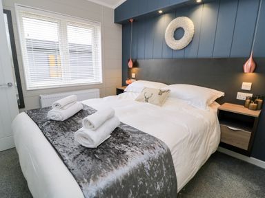 A bedroom with a bed with rolled towels on a throw and bedside tables at The Gallops in Chipping Norton