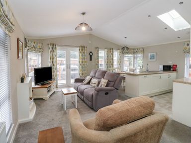 An open living room with couches and a coffee table next to a kitchen island and dining area at Lodge 2 in Auchterarder