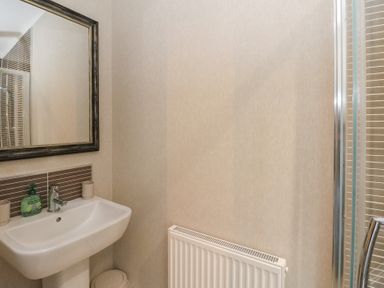 A bathroom with a sink soap dispenser mirror radiator and shower at Lodge 2 in Auchterarder
