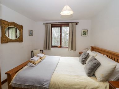 A bedroom with a wooden bed with pillows and folded towels a mirror and two framed pictures on the walls at Wringford Farm Annexe Rame near Kingsand