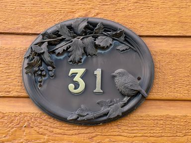 A house number plaque with a bird and leaves at Woodland View 31 - The Hawthorns Finlakes Holiday Park near Chudleigh