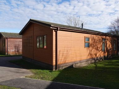 A wooden lodge with windows and a door at Woodland View 31 - The Hawthorns near Finlakes Holiday Park