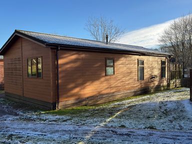 A wooden house with windows and a gate at Woodland View 31 - The Hawthorns Finlakes Holiday Park near Chudleigh