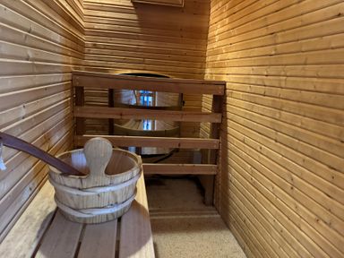 A sauna with wooden bench and bucket at Tor View Finlakes Holiday Park near Chudleigh