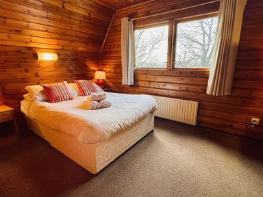 A bedroom with a bed and windows at Tor View Finlakes Holiday Park near Chudleigh
