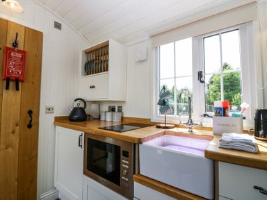 A kitchen with wooden countertops a white sink microwave kettle and window at Airlie Burnside near Forfar