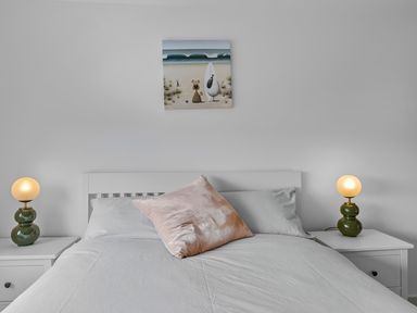 A bedroom with a bed with pillows and bedside tables with lamps at 5 Mermaid Court in Newquay