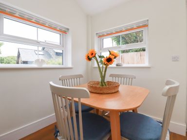 A dining room with a round table and sunflowers at Glendale in Port Isaac