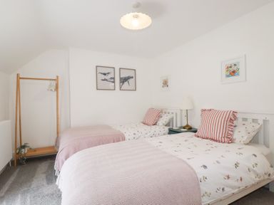 A bedroom with two beds and artwork on the walls at Glendale in Port Isaac