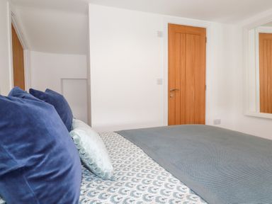 A bedroom with a bed and wooden door at Glendale in Port Isaac