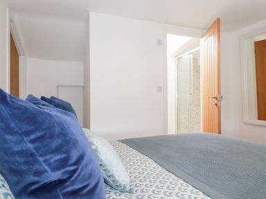 A bedroom with a bed and a door leading to a shower at Glendale in Port Isaac