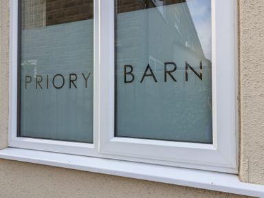 A close up of a window with frosted glass and the words PRIORY BARN on it