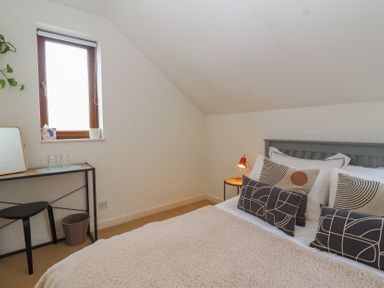 A bedroom with a bed bedside table and a small desk with a chair at Priory Barn Apartment in Walton near Street