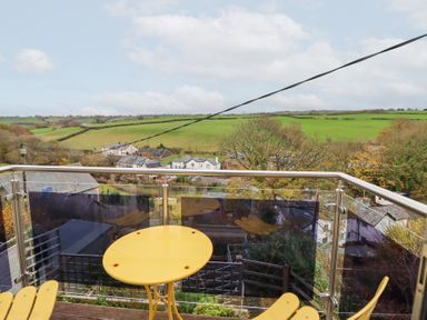 A balcony with a table and chairs overlooking fields at Golygfa in Pandy Tudur near Llanrwst