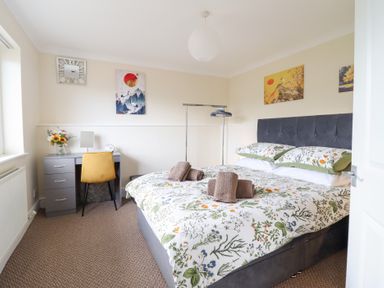 A bedroom with a bed, desk, chair and artwork at Golygfa in Pandy Tudur near Llanrwst